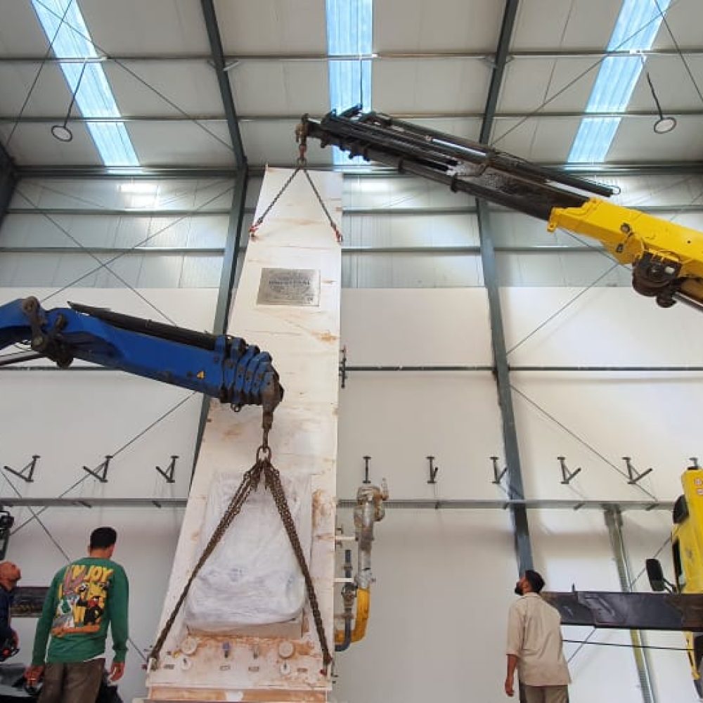 Heavy cranes lifting industrial equipment inside the factory